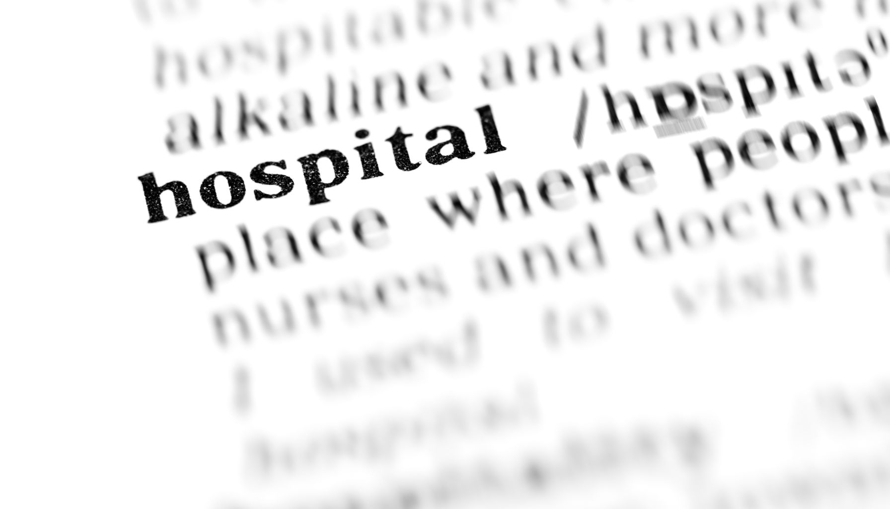 Kartka ze słownika z hasłem hospital i jego wyjaśnieniem. Treść definicji jest rozmyta. Pogrubione i czytelne hasło hospital.