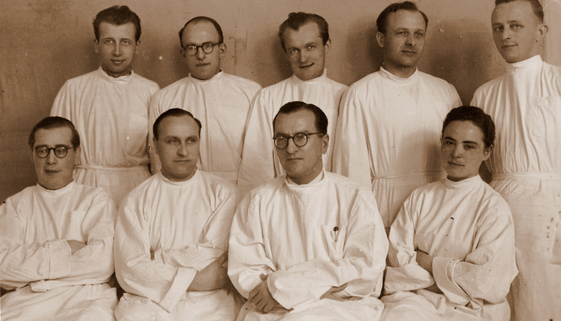 Dziewięciu mężczyzn, jedna kobieta. Wszyscy w białych lekarskich kitlach. Zdjęcie archiwalne
