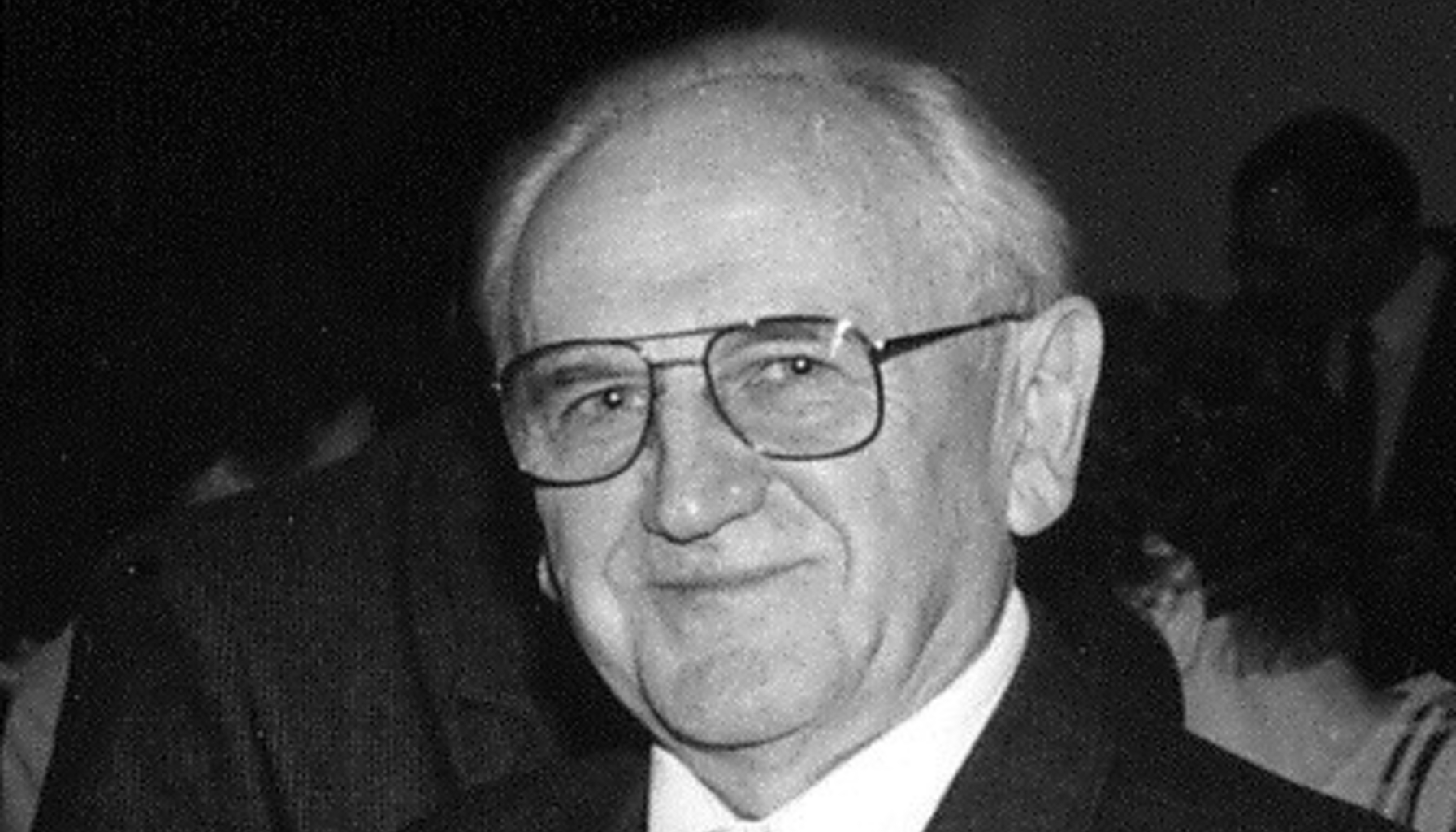 Twarz uśmiechniętego, starszego mężczyzny, elegancko ubranego.