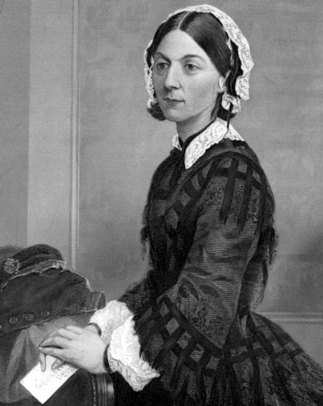 Portretowe zdjęcie Florence Nightingale w czepku i długiej sukni, stojącej bokiem z poważnym wyrazem twarzy.