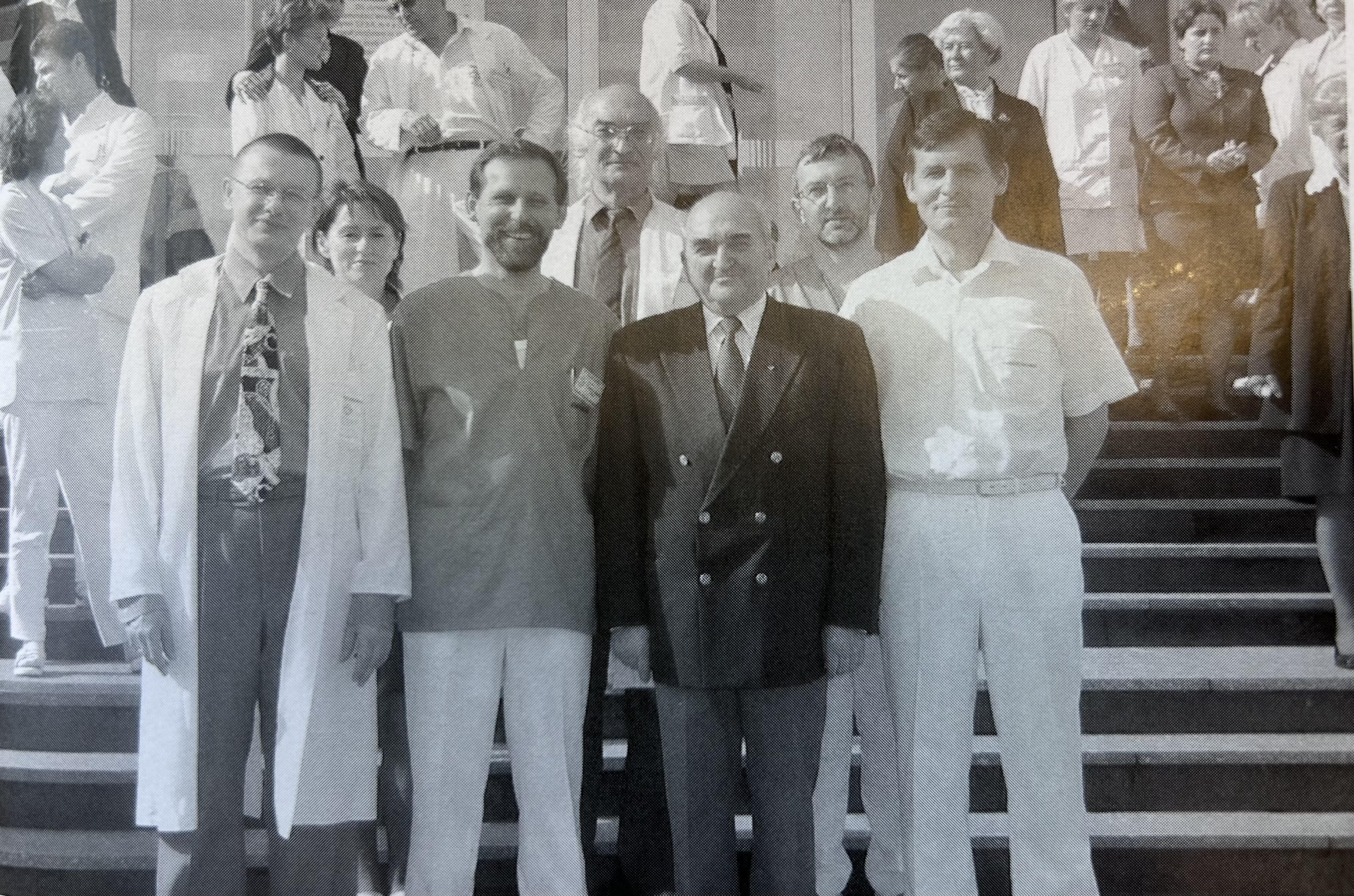 Sześć os&oacute;b na schodach, z tyłu dużo innych os&oacute;b. Wszyscy w kitlach lekarskich lub ubraniach pielęgniarskich