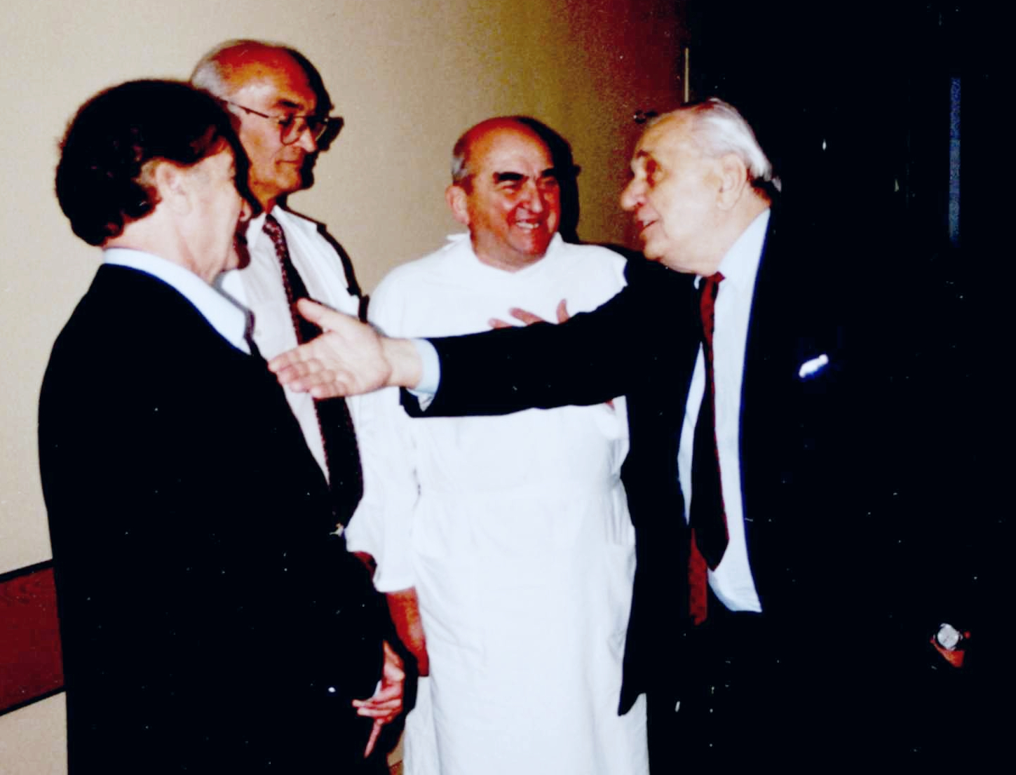 Czterech mężczyzn na korytarzu, jeden wyciąga rękę do drugiego. Od lewej: prof. Wiesław Dubiel, dr n. med. Zygmunt Modrzewski, prof. Stanisław Jabłonka, prof. Zbigniew Papliński