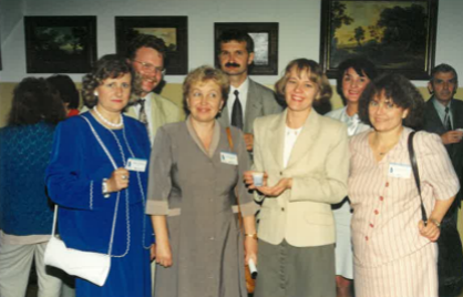 Kilka uśmiechniętych os&oacute;b w eleganckich strojach z lat dziewięćdziesiątych. Zdjęcie niewyraźne.