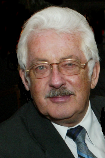 Zdjęcie twarzy starszego pana siwego z wąsem, w okularach, uśmiechniętego.